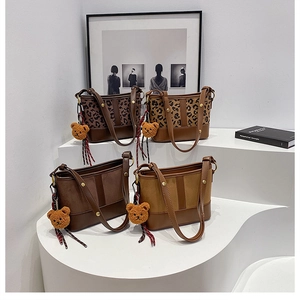 Detailed view of leopard print and solid bucket bags with teddy bear charms on white steps