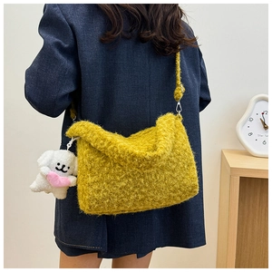 Detail of yellow plush crossbody bag with a cute puppy charm on navy blazer