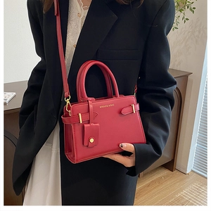 Détail d'un sac à main rouge structuré en cuir mat avec logo doré et finitions chic