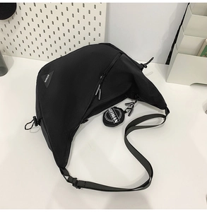 Close-up of black crossbody dumpling bag with triangle logo and mini coin purse