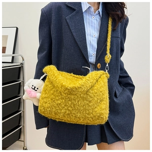 Detail of yellow plush crossbody bag with cute white dog charm on navy blazer