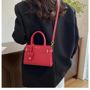 Détail du sac à bandoulière en cuir rouge avec logo de marque et boucle dorée