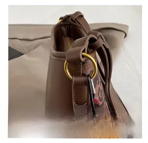 Close-up of golden hardware ring with plush bear charm on leopard print bucket bag