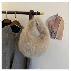 Detail einer weichen beigen Kunstfell-Handtasche an einem Holzkleiderbügel in Minimal-Stil