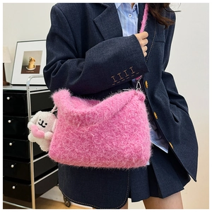 Detailed close-up of a pink faux fur shoulder bag with a cute white puppy doll charm