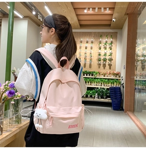 Pink canvas backpack side view with cute cloud pendant on a model in a store