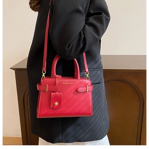 Détail du sac bandoulière vintage rouge avec logo doré et texture de cuir délicate