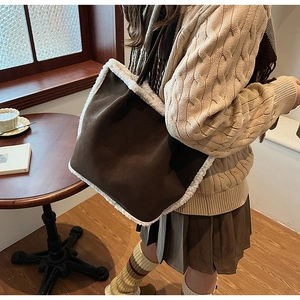 Close-up of a brown suede tote bag featuring white faux fur trim and narrow shoulder straps