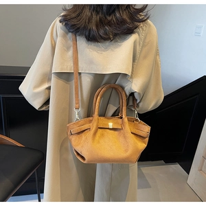 Nahaufnahme der braunen Wildledertasche mit zylindrischem Griff und goldenen Beschlägen