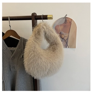Nahaufnahme einer weichen Plüsch-Handtasche aus Kunstpelz an einem Kleiderständer aus Holz
