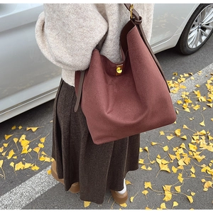 Détail du sac hobo bordeaux à texture mate avec boucle dorée dans un décor d'automne