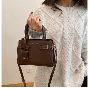 Détail du sac bandoulière en cuir marron avec sangle décorative et boucle métallique