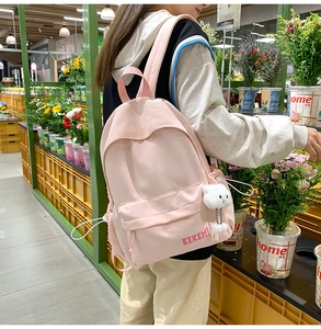 Detail of pink nylon school backpack for girls featuring a white cloud plush charm accessory