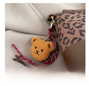 Close-up of teddy bear plush charm with woven rope on leopard print bucket bag