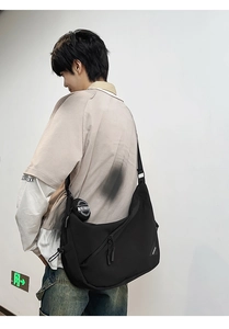 Detail of black crossbody dumpling bag with wide adjustable strap and round coin purse