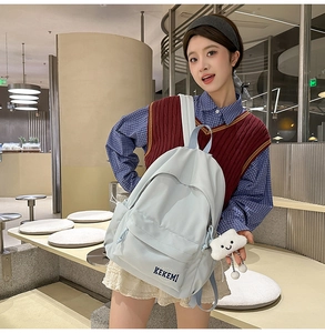 Detail of light blue minimalist backpack with cloud charm and wide straps for students