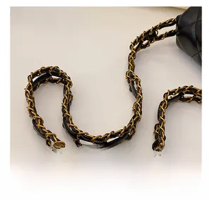 Detail of elegant gold chain strap intertwined with black leather on quilted bag