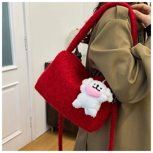 Detail of red plush shoulder bag with cute white puppy charm and soft fluffy texture