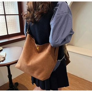 Détail du fermoir tournant doré et de la texture suède sur le sac cabas marron