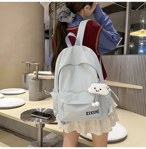 Detail of light blue waterproof backpack with cute cloud charm in a casual cafe setting