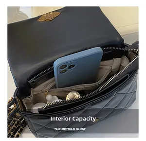 Internal capacity of black quilted shoulder bag showing phone and cosmetics
