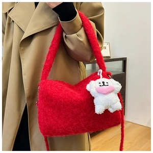 Detail of red plush shoulder bag with a cute white puppy charm and soft furry texture