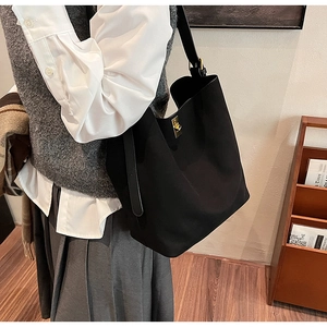 Gros plan d'un sac cabas en daim noir avec fermoir doré et bandoulière large