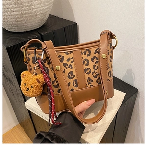 Detail of leopard print bucket bag featuring gold rivets and a cute teddy bear charm