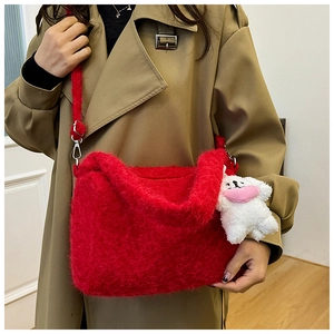 Close-up of fluffy red plush tote bag with a cute white heart plush charm on a beige trench coat