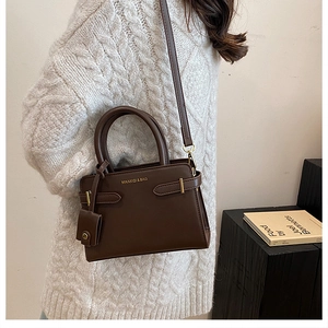 Détails d'un sac à main rétro marron avec boucles dorées et poignée en cuir élégante