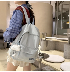 Detail of light blue waterproof nylon backpack with a cute white cloud plush pendant