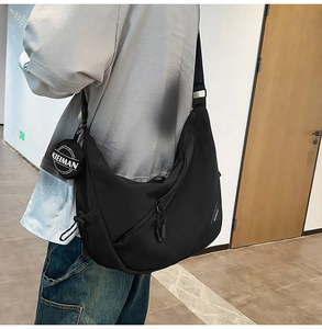 Detailed view of black crescent crossbody bag with mini pouch and KIEIMAN logo