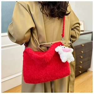 Detail of red plush shoulder bag with long faux fur texture and a cute sheep keychain