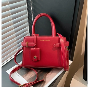 Vue détaillée du sac à main en cuir rouge avec logo doré et boucles de sangle