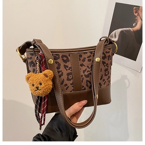 Detail of leopard print bucket bag featuring brown leather trim and cute bear charm