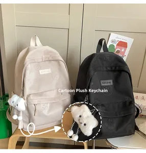 Detail view of two nylon backpacks with cartoon plush pendants and letter prints