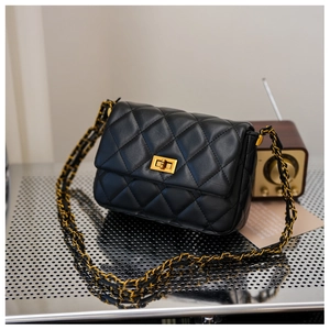 Close-up of quilted leather texture and golden metal clasp on black crossbody bag