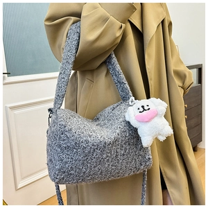 Detail of gray woven crossbody bag with a cute white plush puppy charm on a model
