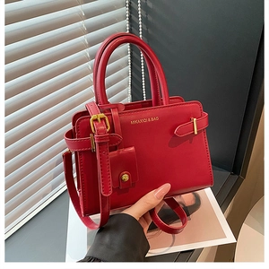 Détail du sac à bandoulière en cuir rouge avec accessoires dorés et sangle