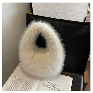 Detailansicht der elfenbeinfarbenen Plüschtasche auf schwarzem Stuhl mit Büchern