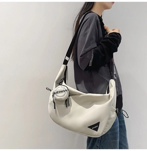 Detail showing the adjustable black shoulder strap and side mini round pouch on the bag