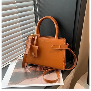 Vue détaillée du sac à bandoulière en cuir marron avec logo doré et boucles de côté