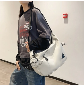 Close-up of white crossbody dumpling bag with triangle logo and round coin purse accessory