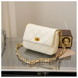 Close-up of cream quilted leather texture and gold metal turn-lock on a shoulder bag
