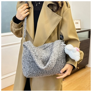 Detail of grey fleece crossbody bag with white plush charm and wide shoulder strap