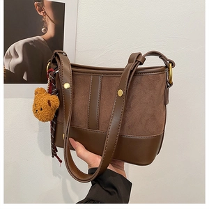 Detail of vintage brown bucket bag with plush bear charm and sleek gold metal ring