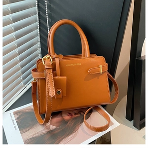 Détail du sac à main caramel avec boucles décoratives et petit porte-monnaie accessoire
