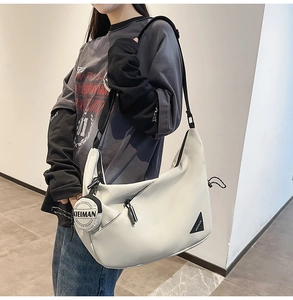 Model wearing a minimalist cream dumpling messenger bag with black logo and strap
