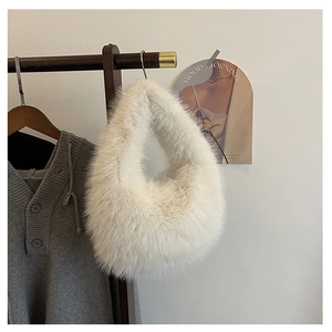 Detailaufnahme einer weißen flauschigen Kunstpelz-Handtasche an einer Holzstange für Winter