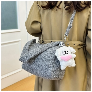 Detail of grey textured shoulder bag with silver buckle and plush puppy charm